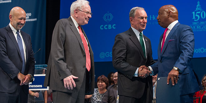 photo of Goldman CEO, Warren Buffett, and Michael Bloomberg congratulating one of the program graduates