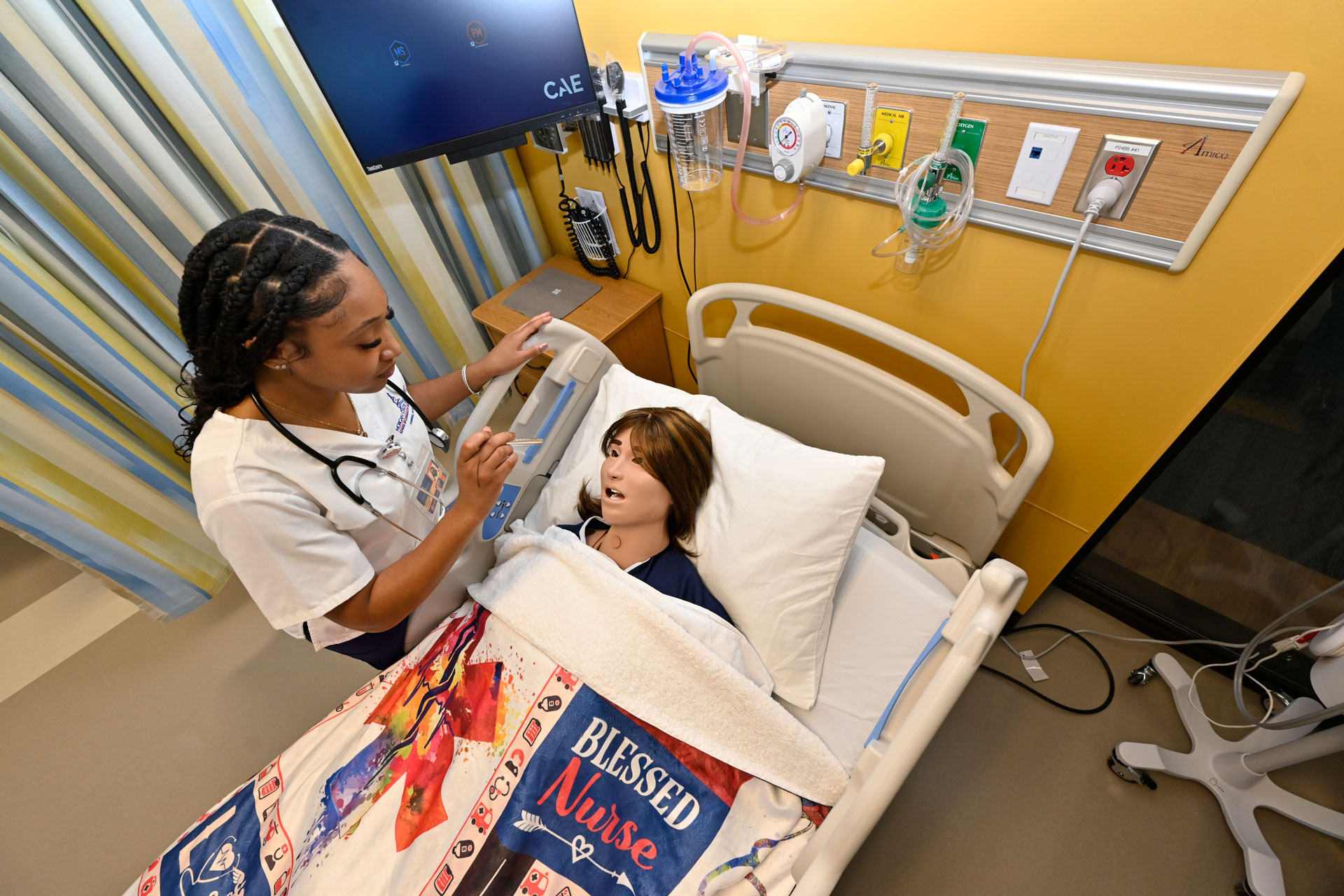 A Morgan State nursing student practices taking vital signs on a medical mannequin in the nursing simulation lab in the Health and Human Sciences Building