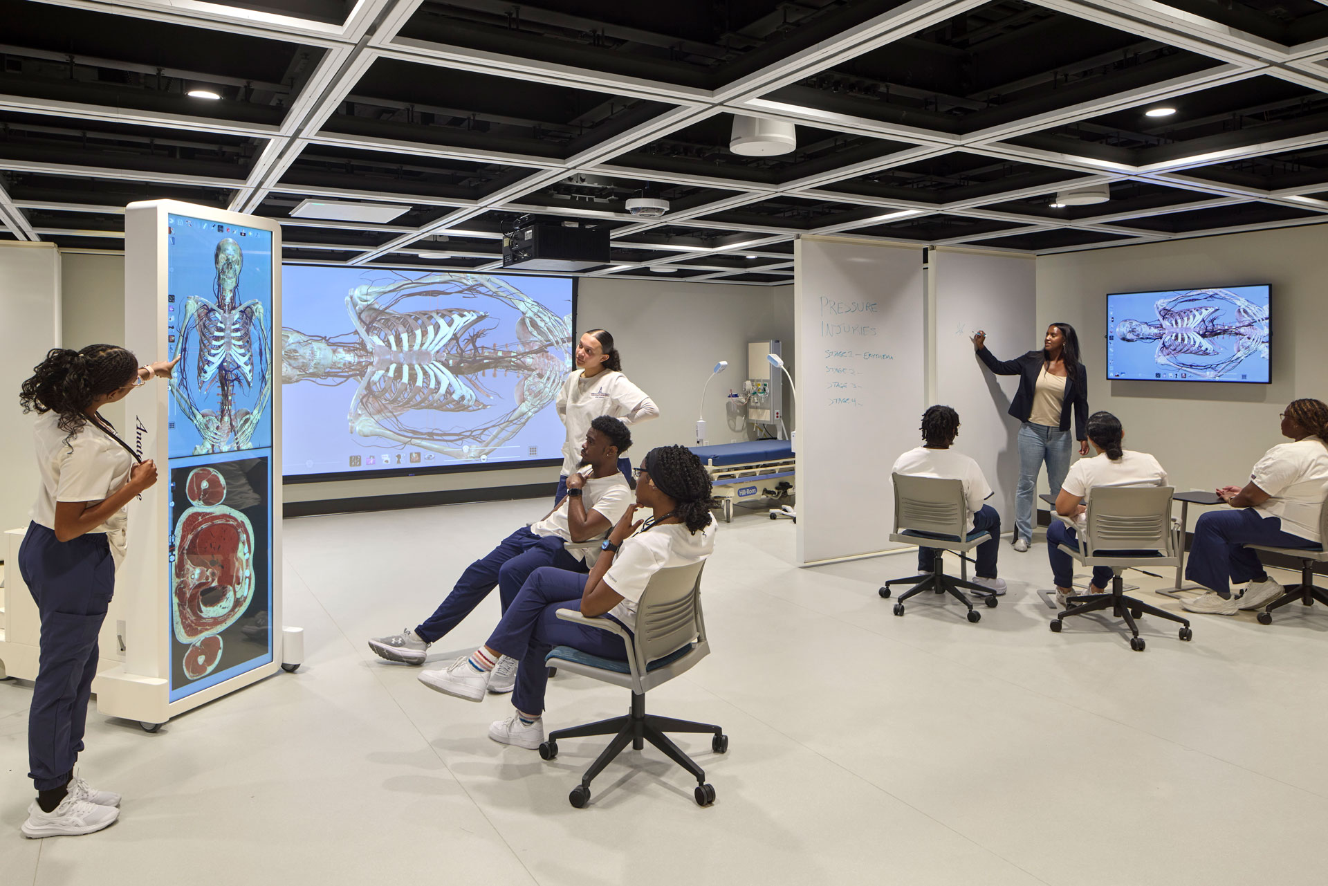 Nursing students at Morgan State University engage in an interactive anatomy lesson inside a modern simulation lab, featuring digital displays of skeletal and muscular systems